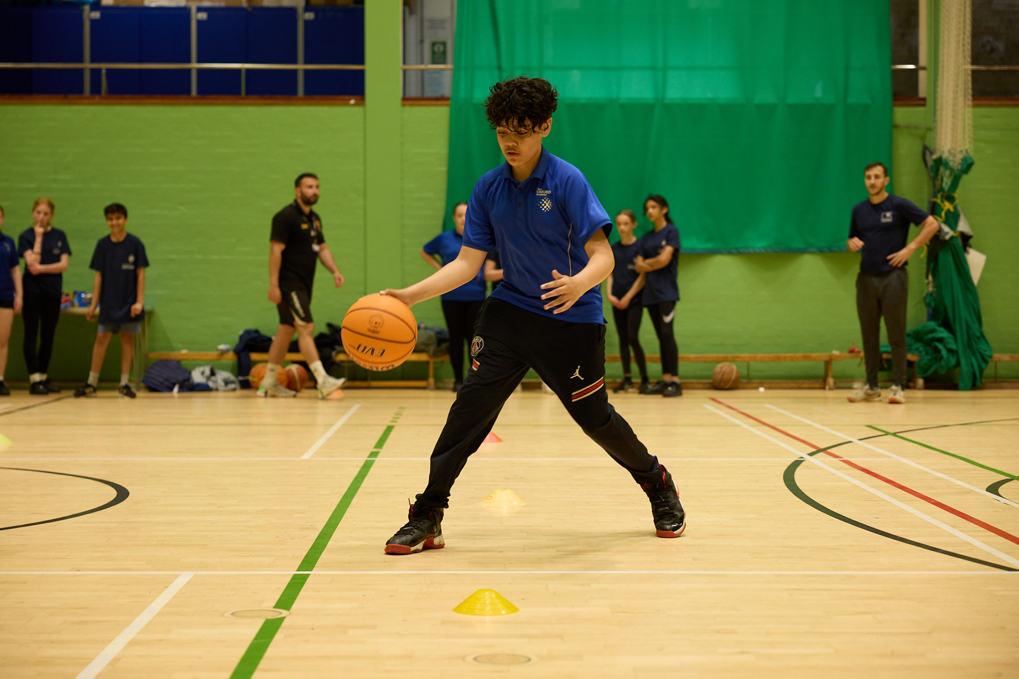 Pupil in a school hall bouncing a basketball