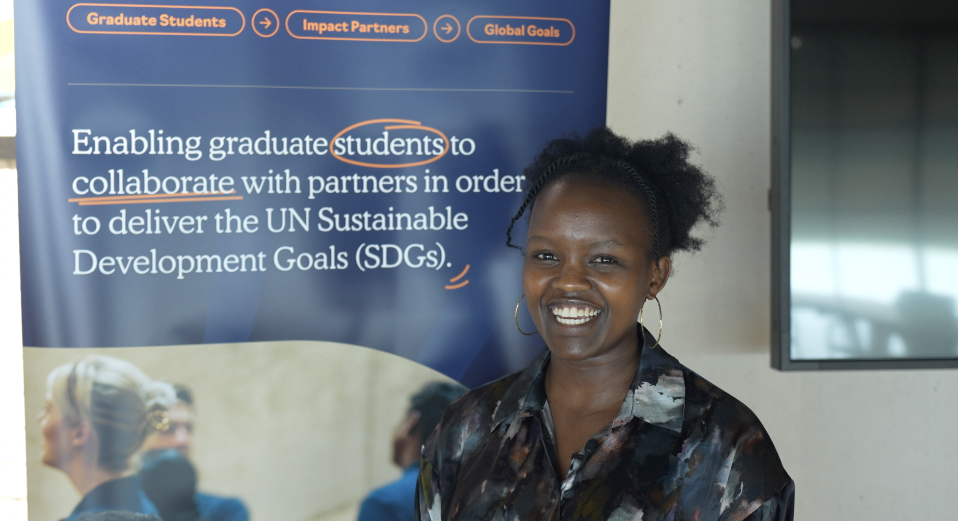 Dorcas Tuitoek smiling during an interview infront of an SDG Impact Lab banner