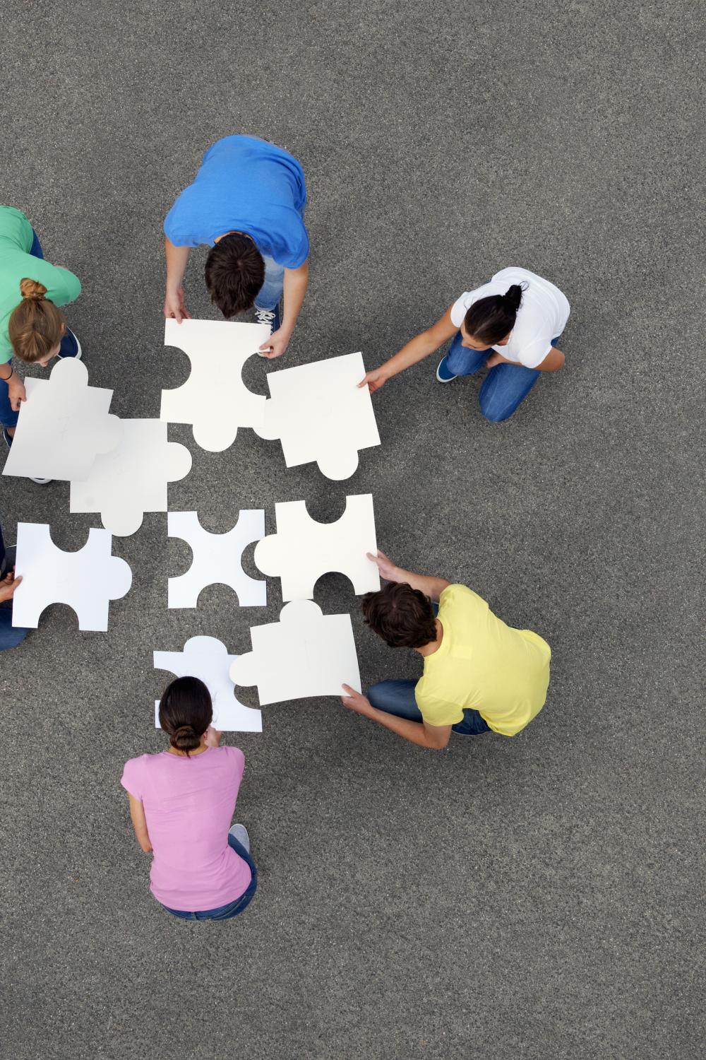 6 people holding together jigsaw pieces