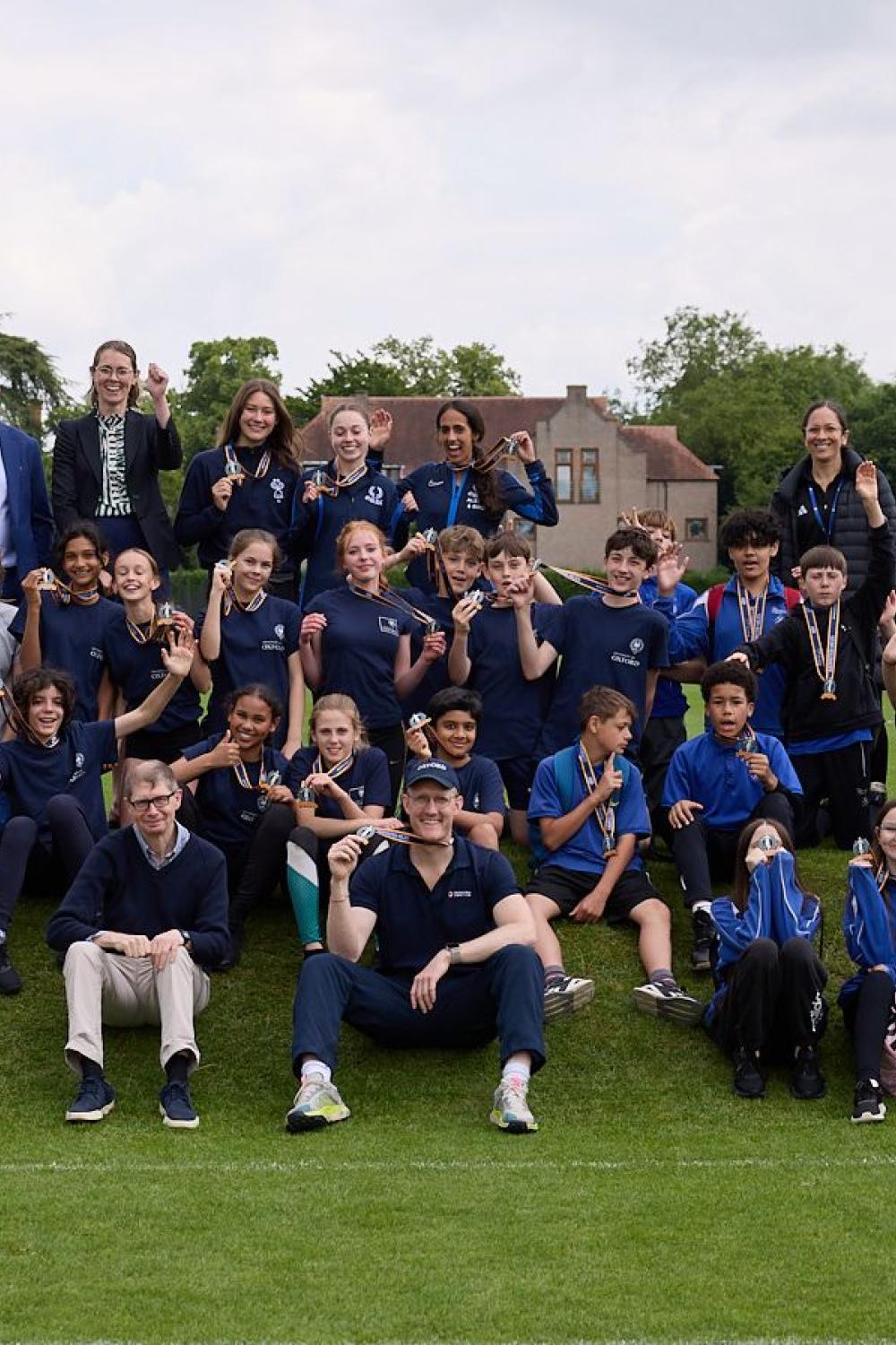 Sports Students and Faculty sitting on the hill with medals 