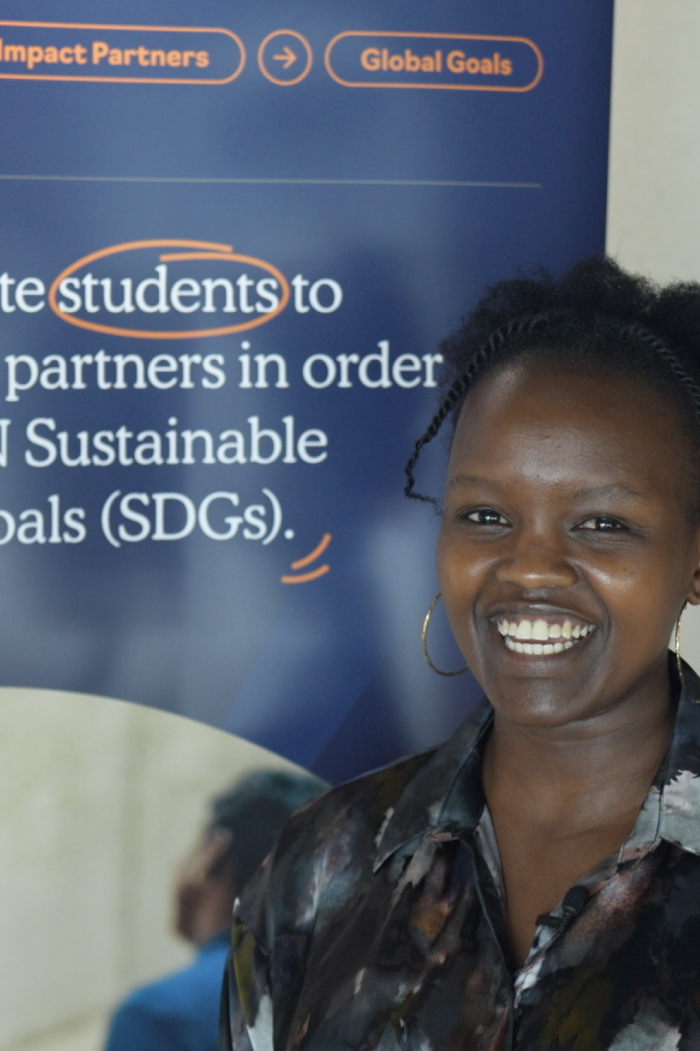 Dorcas Tuitoek smiling during an interview infront of an SDG Impact Lab banner