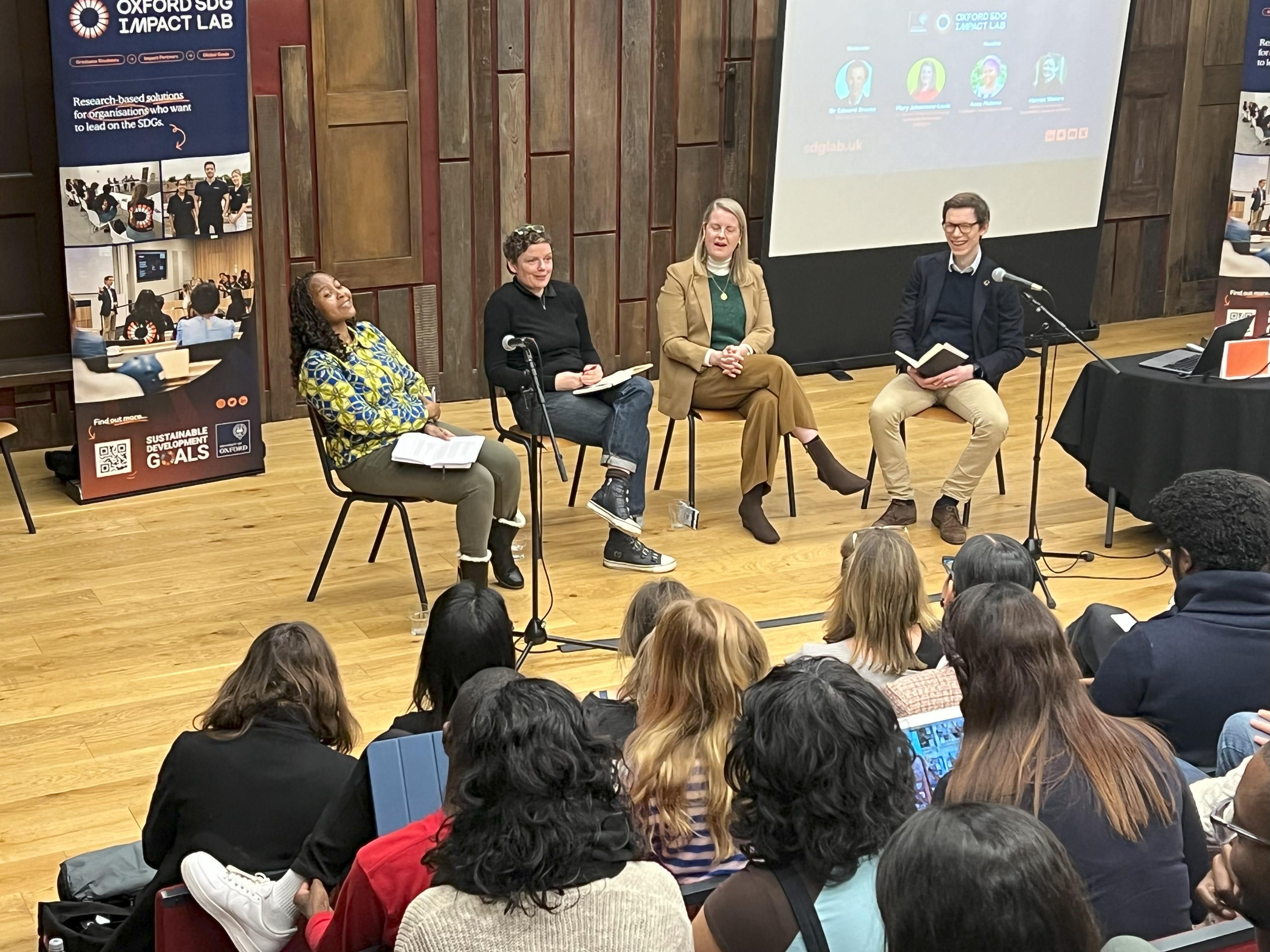 Panel smiling during conversation at front of lecture theatre