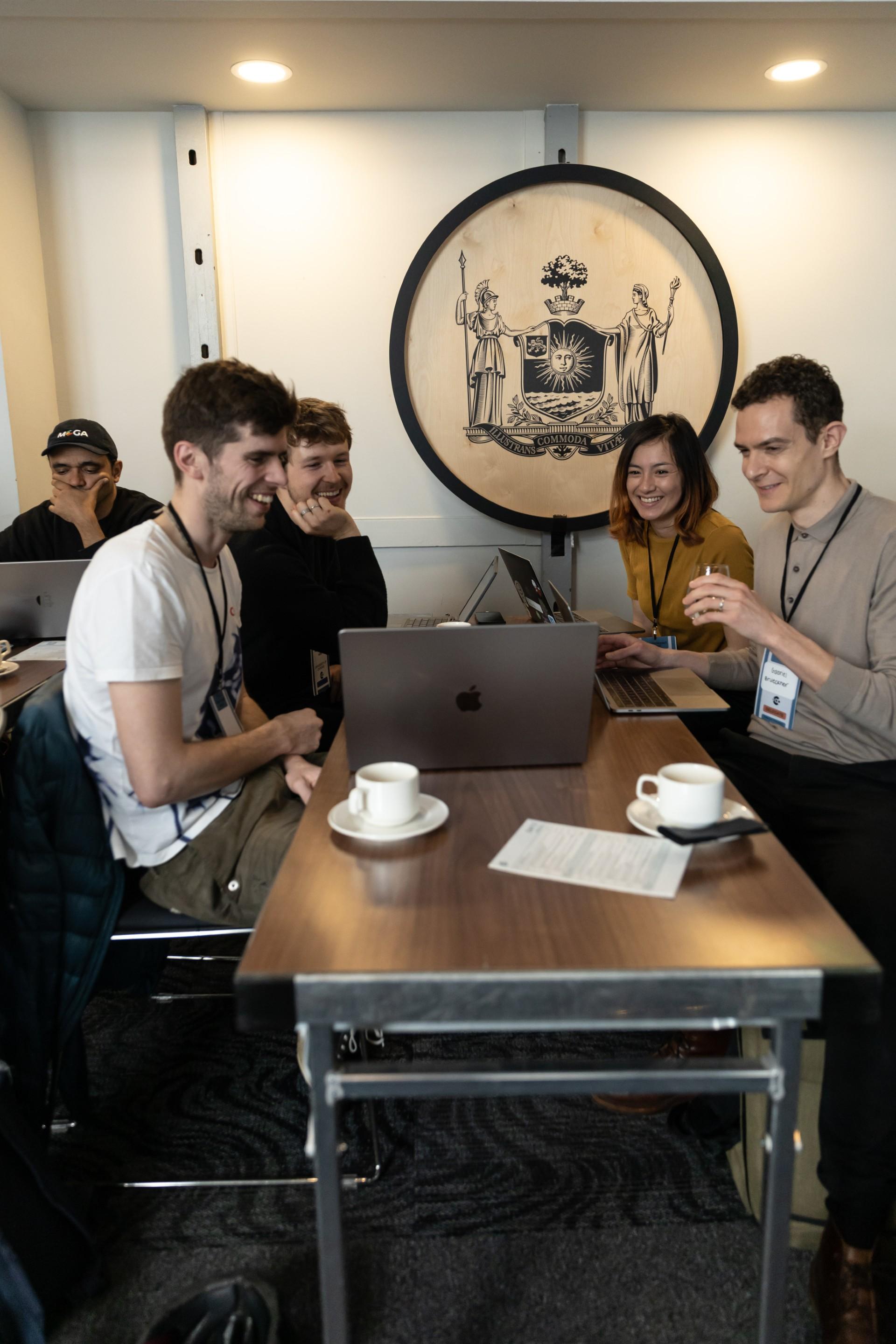 Miles Judd seated at table with 3 others at the AI Hackathon event