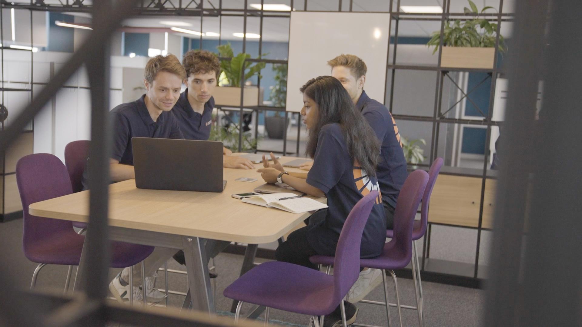 Aurona and Tilmann working at a laptop in a group at the MINI plant